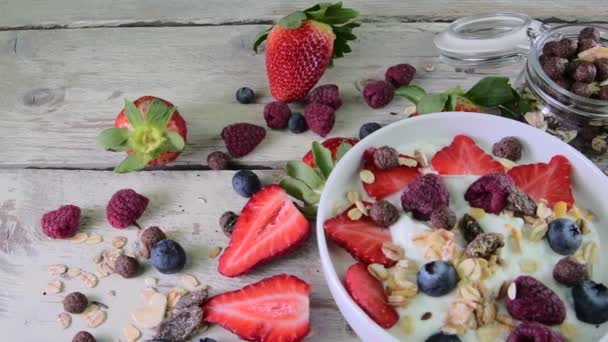 Samenstelling van een typisch echte ontbijt met yoghurt, bosbessen, frambozen, bosbessen, muesli gemaakt. Begrip: fitness, voeding, wellness en ontbijt. Bovenaanzicht - Video
