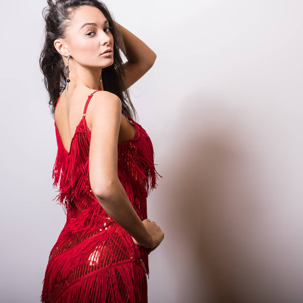 Young sensual woman in red dress pose in studio. - Fotó, kép