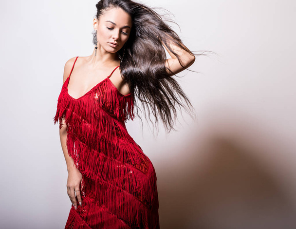 Young sensual woman in red dress pose in studio. - Фото, изображение