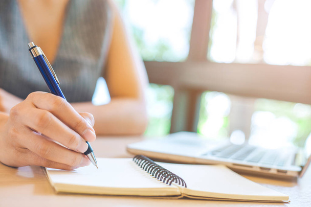 Рука ділової жінки пише на блокноті з ручкою в офісі
. - Фото, зображення
