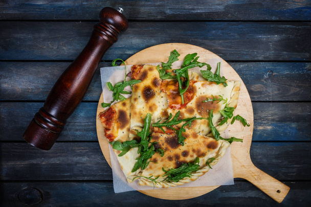 Calzone - Pizza ripiena con prosciutto, funghi, rucola e formaggio
. - Foto, immagini