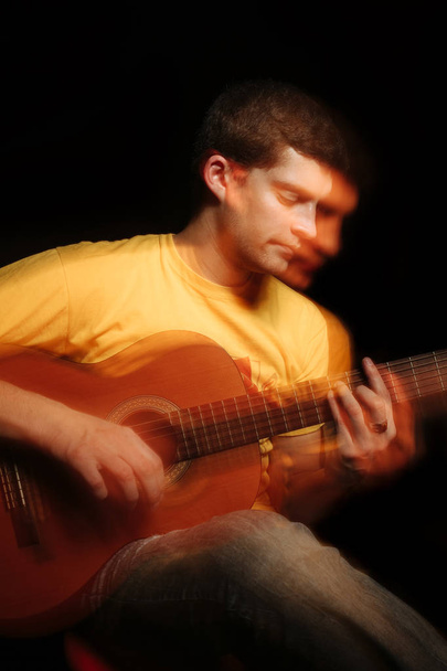 ハンサムな若いミュージシャンがギターで演奏します。二重露光のコンセプト. - 写真・画像