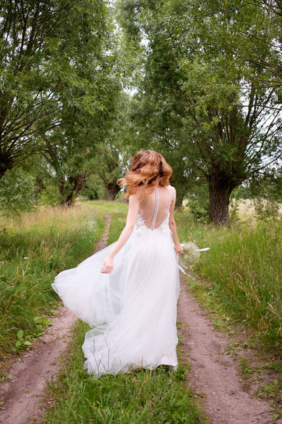 bride in white llight wedding dress with bridal bouquet running  - Фото, изображение