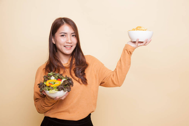 Young Asian woman with potato chips and salad. - Photo, Image