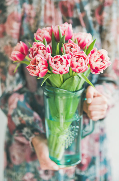 Spring flowers arrangement. Woman in colorful silk dress holding bouquet of fresh pink tulips. Florist shop, Woman's day greeting card concept - Fotó, kép