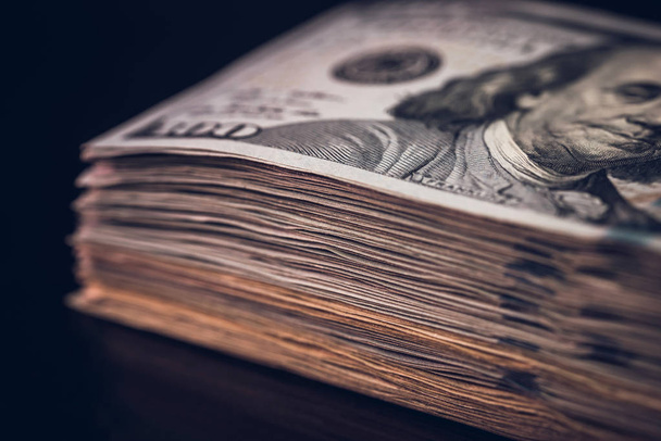 банкноты по 100 долларов США с полосой на черном фоне
. - Фото, изображение