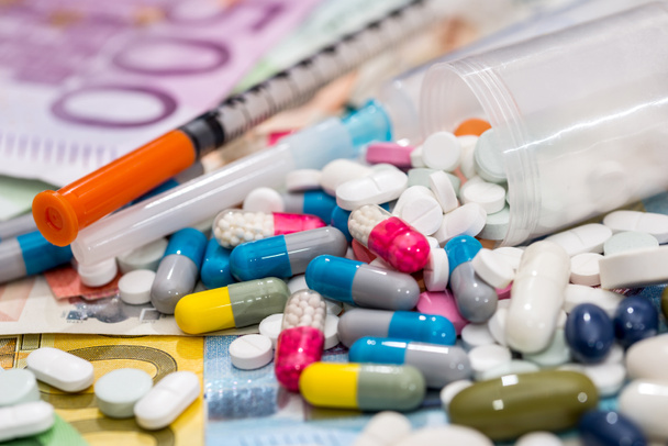 pills  with syringe above euro bills. Medicine cost. - Foto, afbeelding