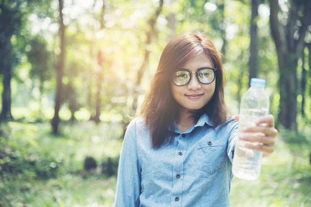 mooi meisje drinkt water uit een fles op de aard - Foto, afbeelding