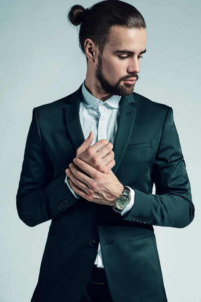 portrait of handsome fashion stylish hipster lumbersexual businessman model dressed in elegant black suit posing on studio background. Metrosexual - 写真・画像