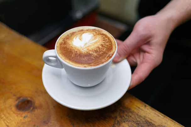 Mão barista segurando e servindo xícara de café
. - Foto, Imagem