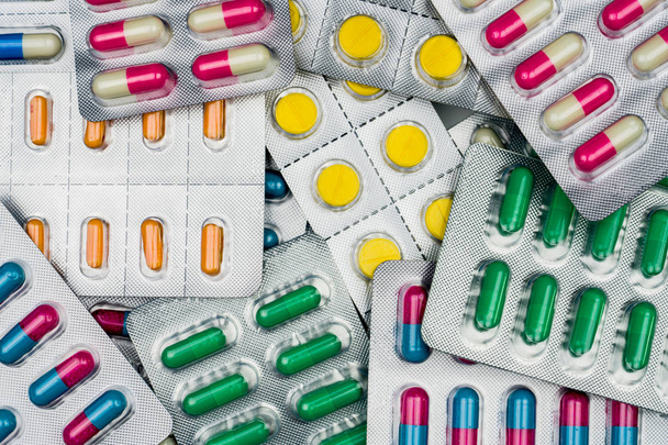 Bovenaanzicht van kleurrijke tabletten en capsules pillen in blisterverpakkingen. Wereldwijde gezondheidszorg en drug gebruiken met redelijke concept. Volledige frame van stapel van pillen - Foto, afbeelding