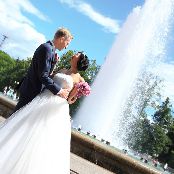 portrait of the bride and groom standing near the fountain. - Foto, Imagem