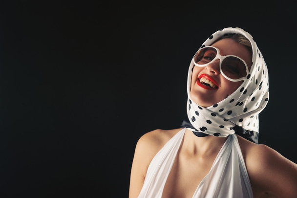 Retro woman with sunglasses laughing fashion portrait against black background - Photo, image