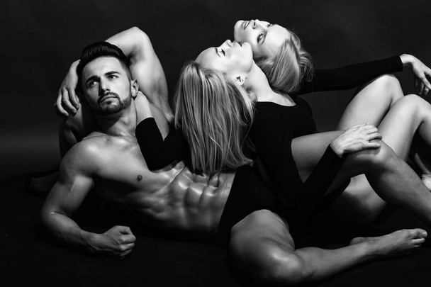 love relations of man with muscular body with twin girls - Φωτογραφία, εικόνα