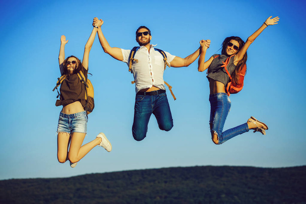 friends, happy tourists jumping on mountain top on blue sky - Zdjęcie, obraz