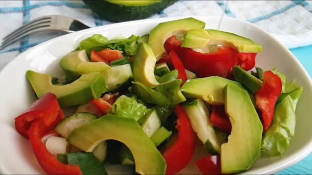 salade met avocado en sesam zaden, olie wordt gegoten, op een houten - Video