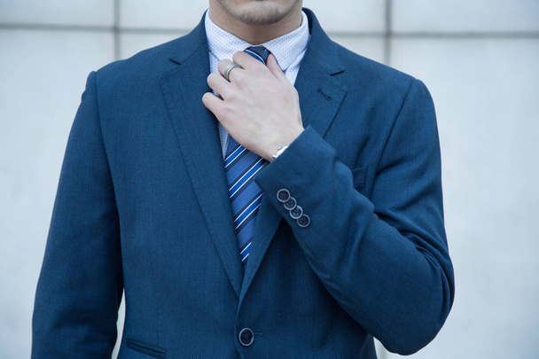 Jonge zakenman gekleed in pak op een witte achtergrond met lijnen van een gebouw. - Foto, afbeelding