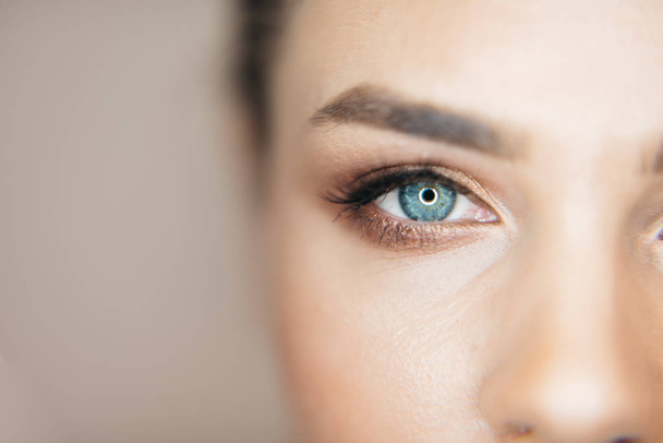 Primo piano di colpo di bel occhio azzurro della donna fresca attraente con trucco naturale a sfondo beige. Parte del viso sano
. - Foto, immagini