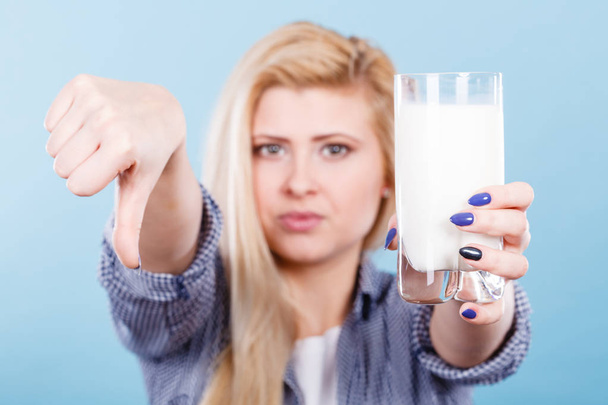 Woman holding milk glass showing thumb down - Foto, afbeelding