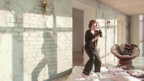 Σέξι Λατίνα γυναίκα με ακουστικά που χορεύουν στο υπνοδωμάτιο φοράει μετάξι pajama. - Πλάνα, βίντεο