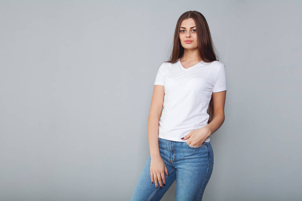 Mooi meisje in wit t-shirt met lang en mooi haar op een donkere achtergrond, emotie. Mock-Up - Foto, afbeelding