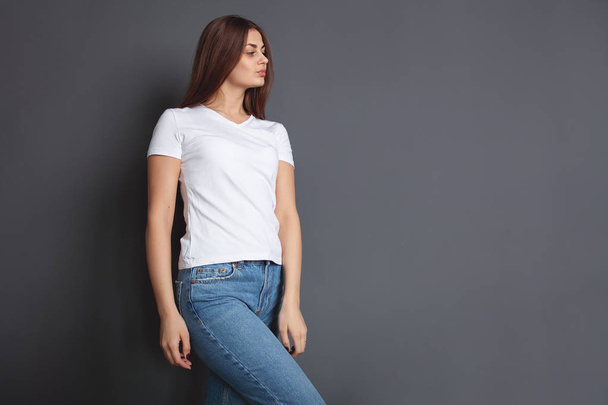 Mooi meisje in wit t-shirt met lang en mooi haar op een donkere achtergrond, emotie. Mock-Up - Foto, afbeelding