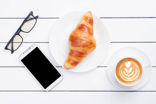 coffee croissant phone laptop view from above white background - Zdjęcie, obraz