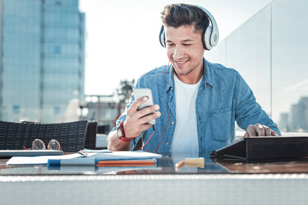 Smiling freelancer turning music while working outdoors - Foto, Bild