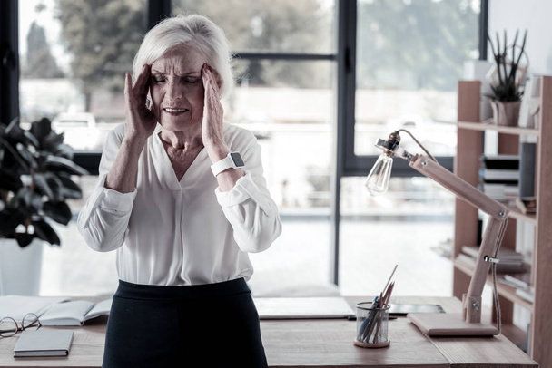 müde ältere Büroangestellte mit Kopfschmerzen - Foto, Bild