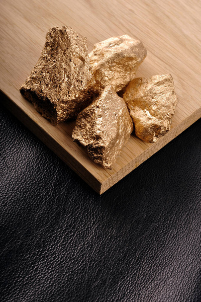 Gold nuggets on a black background leather and wood. Closeup. - Fotoğraf, Görsel