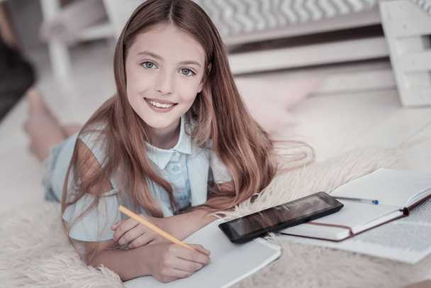 Cheerful girl drawing while lying on the floor - Foto, Imagen