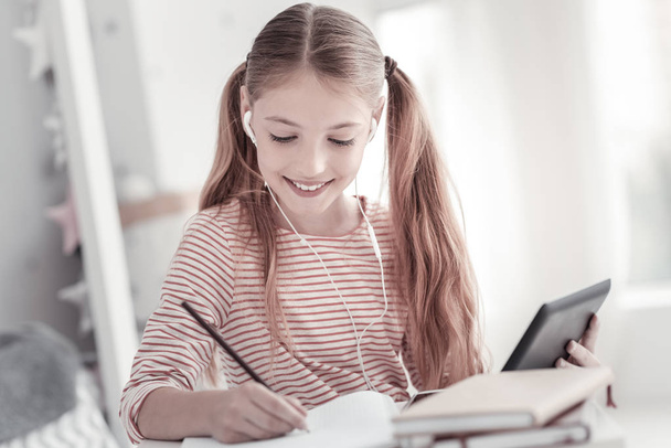 Exuberant girl writing and holding her tablet - Foto, afbeelding
