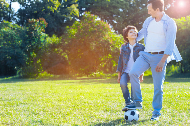 Rakastava isä syleilee poikaa pelattuaan jalkapalloa
 - Valokuva, kuva