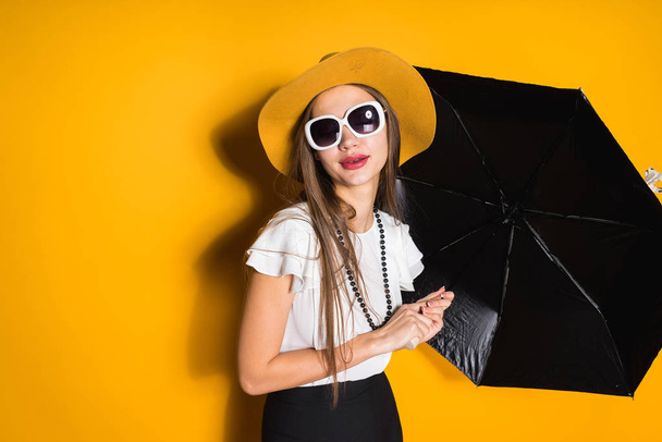 pensive woman in a hat holds a black umbrella in hands - Fotografie, Obrázek
