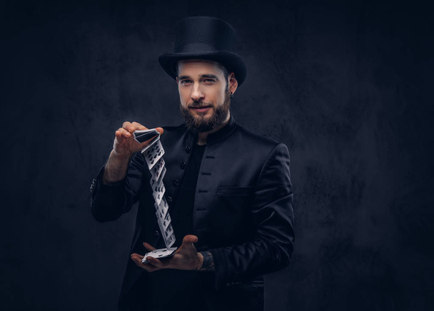 Magician showing trick with playing cards on a dark background. - 写真・画像