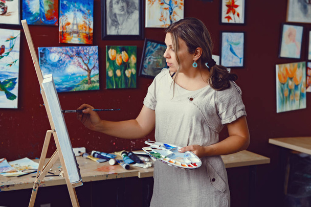 Portré fiatal gyönyörű középkorú fehér-kaukázusi nő művész rajz-festészet-művészeti stúdió, akril festékek, vászon. Életmód tevékenység hobby koncepció - Fotó, kép