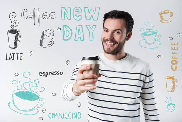 Pozitív fiatalember gazdaság egy pohár kávét, és boldog - Fotó, kép
