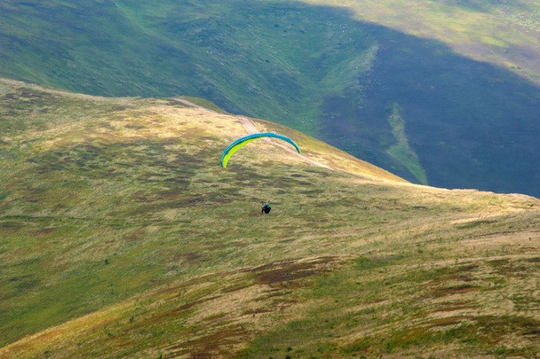 El parapente vuela sobre un valle montañoso en un soleado día de verano. Parapente en los Cárpatos en el verano
.  - Foto, Imagen