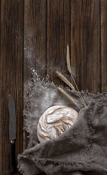 close-up of Freshly baked traditional bread with flour and wheat on wooden background - Fotó, kép