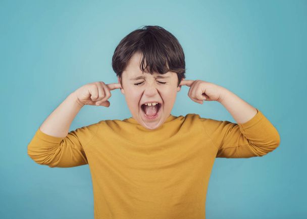 Porträt eines schreienden kleinen Jungen, der Ohren mit Händen bedeckt - Foto, Bild