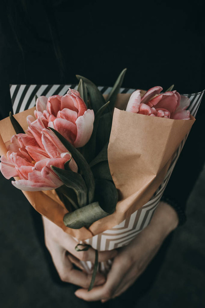 Femme main tenant bouquet de fleurs de tulipes rose doux décoré avec du papier kraft
 - Photo, image