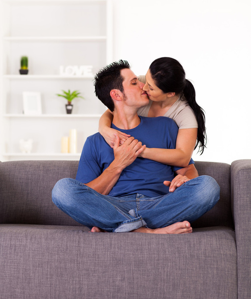 Young couple kissing on sofa at home - Foto, imagen