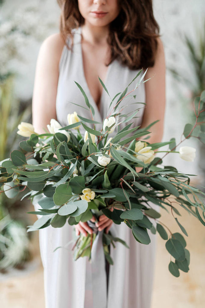 Lush bouquet of eucalyptus and tulips in the hands of the bride - Foto, Imagen