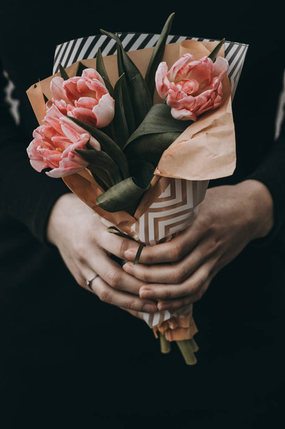 Woman hand holding soft pink tulips flowers bouquet decorated with kraft paper - Zdjęcie, obraz