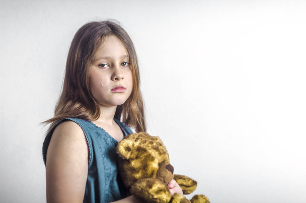 Offended little girl cries, holding a bear in her hands. - Photo, Image