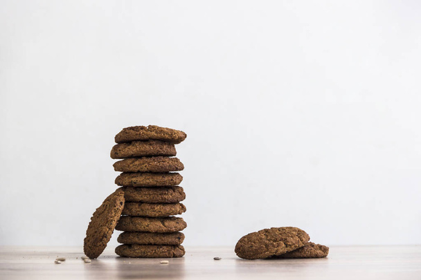 on a wooden table on a white background stands a stack of oatmeal cookies sunflower seeds - Photo, image