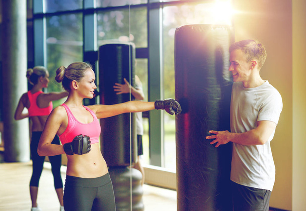 smiling woman with personal trainer boxing in gym - Foto, afbeelding