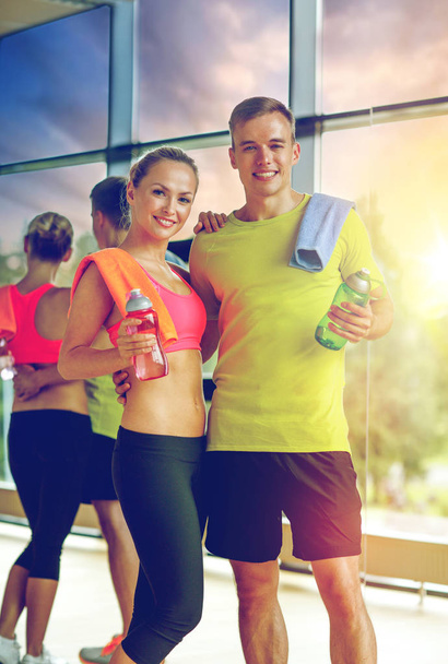 smiling couple with water bottles in gym - Photo, Image