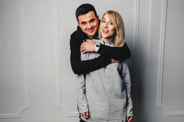 Giovane coppia che abbraccia e posa su uno sfondo leggero
 - Foto, immagini