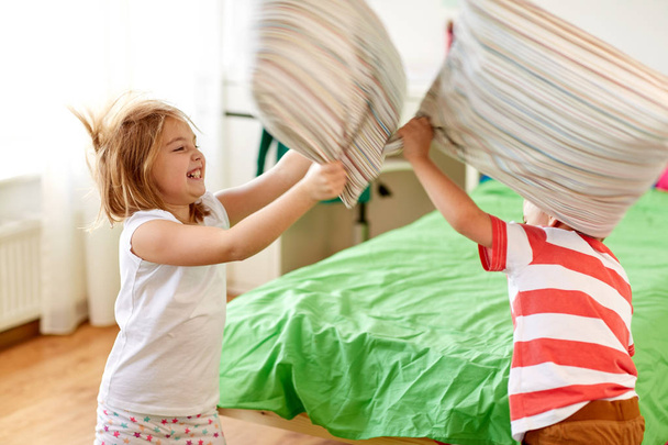 kids playing and fighting by pillows at home - Фото, изображение